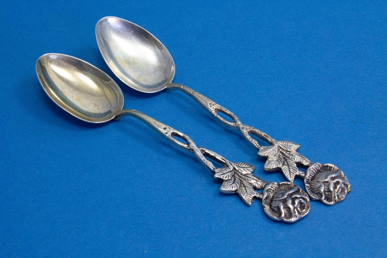 2 silver teaspoons with a rose pattern